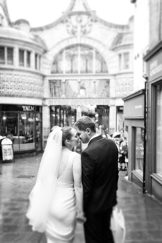 Bride and groom walking away through a European-style covered arcade during their wedding day