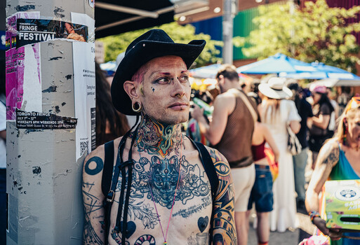 Heavily tattooed man wearing black cowboy hat at outdoor festival