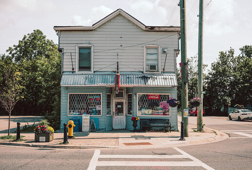 Turquoise storefront with white upper facade and flower boxes in street-level photograph