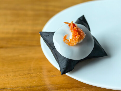 Plated shrimp on white ceramic dish with black fabric accent on wooden surface