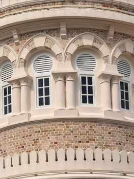 Curved neoclassical building facade with arched windows and brick detailing