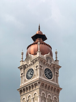 Clock tower with copper dome and cream-colored stone facade against overcast sky