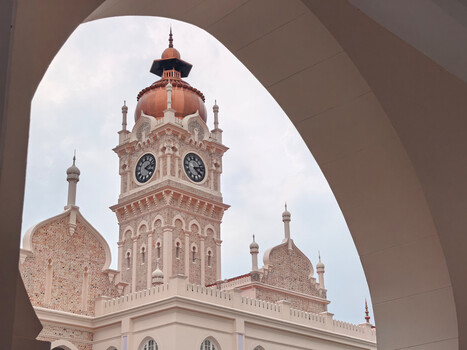 Ornate clock tower framed through curved architectural archway