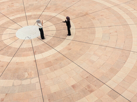 Bride and groom standing on geometric paved plaza with radiating line pattern