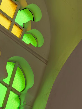 Green neon semicircular lights mounted on a wall with yellow accent lighting