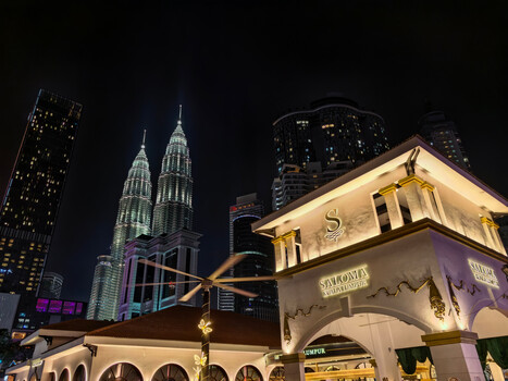 Kuala Lumpur skyline at night with illuminated Petronas Twin Towers and colonial-style building in foreground