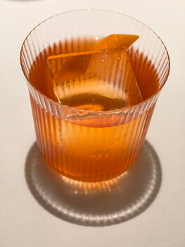 Amber-colored liquid in a ribbed glass with creased sides on a metallic base