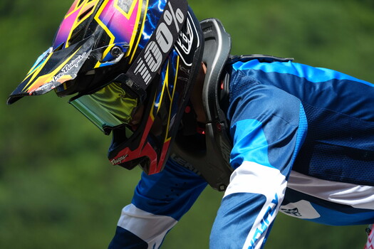 Motocross rider in blue gear holding colorful helmet with vibrant graphics