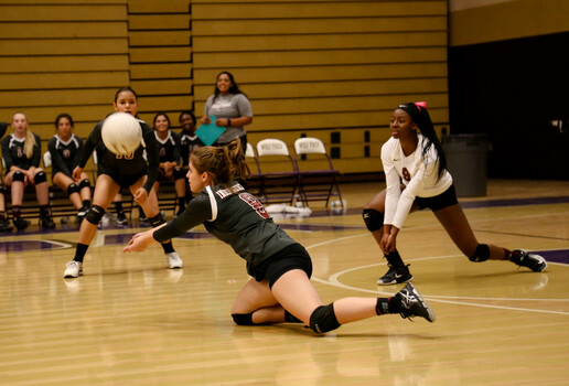 Female volleyball player diving horizontally to pass the ball during indoor match