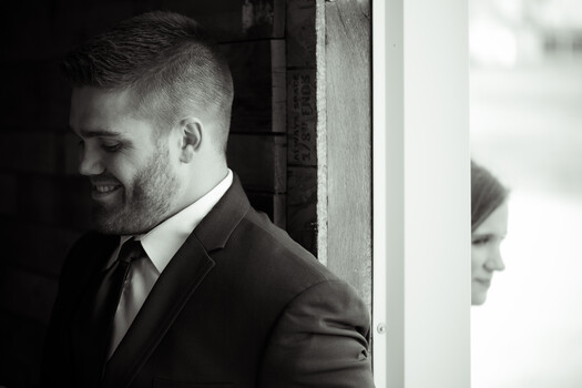Bearded man in business suit smiling in profile, shot in monochrome with dramatic side lighting