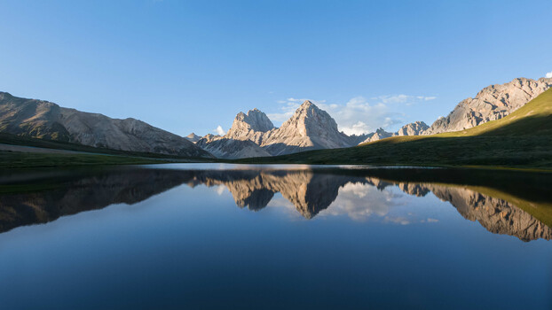 Mountain peaks reflected in still alpine lake at golden hour