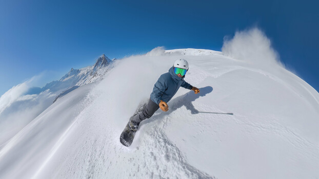 Skier in mid-air performing aerial maneuver on steep snow-covered mountain slope