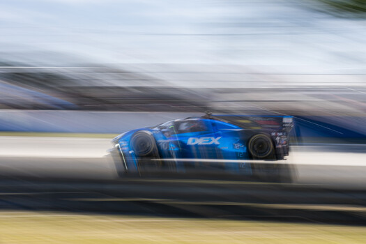 Blue race car captured with motion blur technique during high-speed track movement
