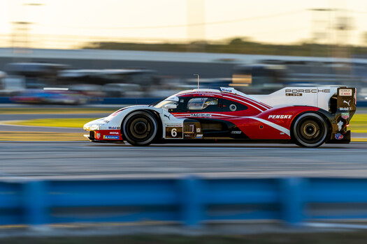 Red and white Porsche prototype race car in motion on track with motion blur