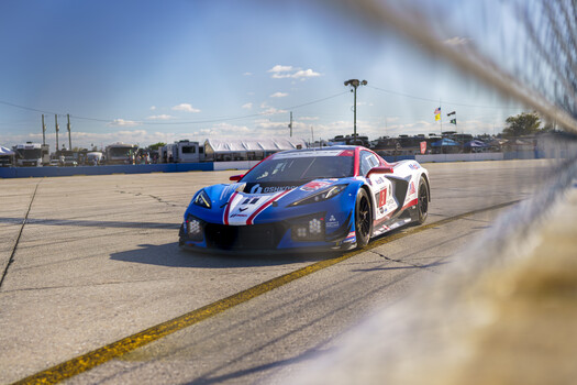 Red and blue racing car on a racetrack with barrier in foreground