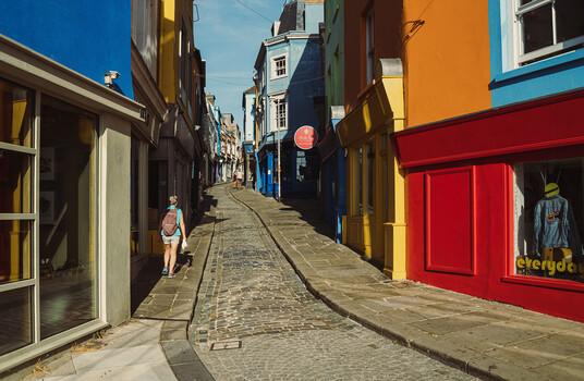 Narrow cobblestone street lined with colorful historic buildings in blue, yellow, orange, and red