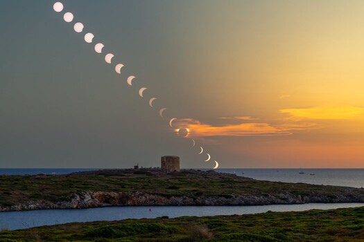 Lunar eclipse progression composite photographed above coastal landscape at sunset