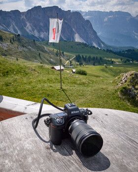 Nikon DSLR camera with telephoto lens on white surface overlooking Alpine valley