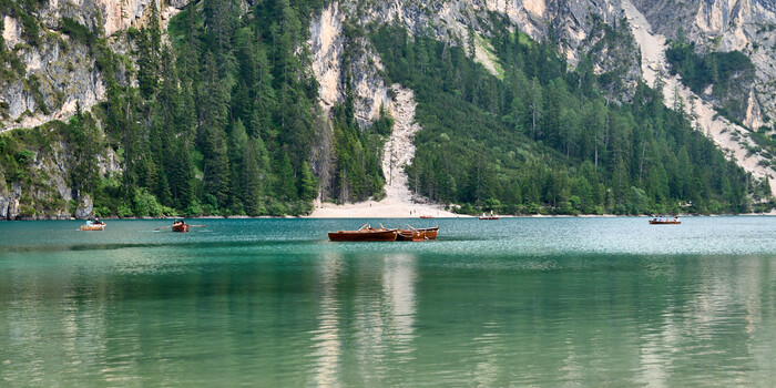 Turquoise alpine lake with wooden boats and forested limestone cliffs
