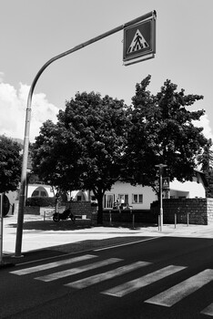 Pedestrian crossing with triangular warning sign mounted on curved street lamp