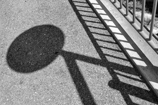 Shadow of person holding tennis racket cast on textured concrete surface