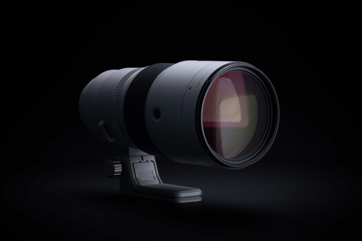 Professional telephoto lens with prominent front element against black background