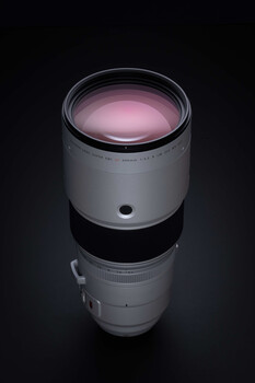 White telephoto lens with pink optical glass elements displayed vertically against black background