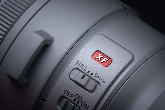 Close-up of camera lens controls showing XF button, autofocus mode switch, and distance scale markings