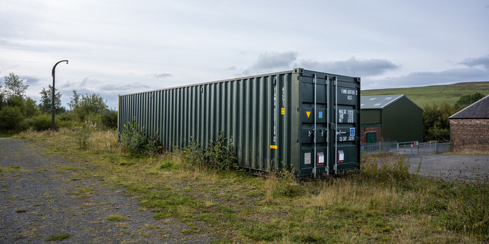 Industrial shipping container converted into a structure in a rural Scottish landscape