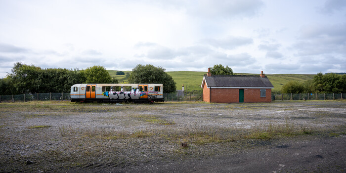 Abandoned passenger train car and brick building in rural Scottish landscape