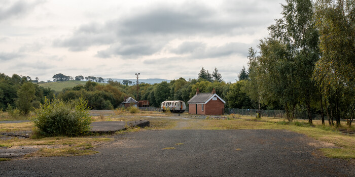 Rural farmstead with red barn and outbuildings beside a paved driveway, surrounded by trees and open fields