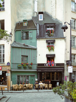Charming Parisian street corner with a narrow mint-green storefront and bistro seating