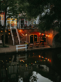 Candlelit outdoor seating area reflected in still water at dusk