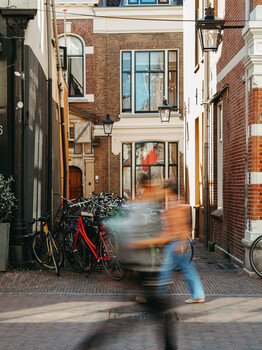 Blurred figure moving through narrow European brick alleyway between period buildings