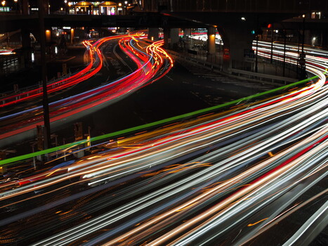 Long exposure light trails from vehicle traffic flowing through an urban intersection at night