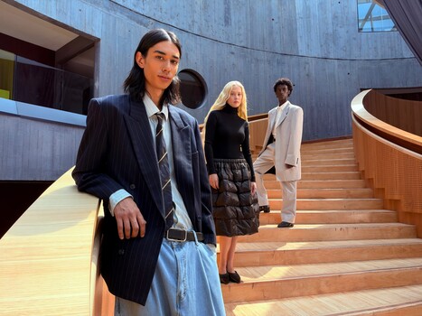 Four people in business and smart casual attire positioned on a modern wooden staircase with concrete walls