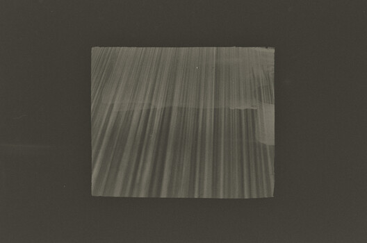 Abstract photograph showing diagonal light streaks and linear patterns on translucent surface
