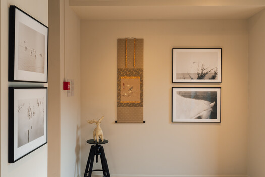 Gallery wall with framed black and white photographs and Asian scroll art above a decorative deer sculpture