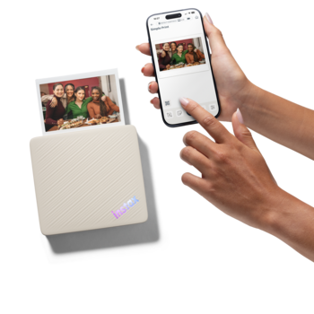 Portable photo printer with printed photo next to smartphone displaying the same image