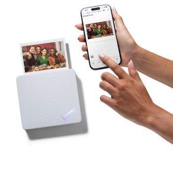 Portable photo printer with instant prints next to smartphone displaying the same family photo