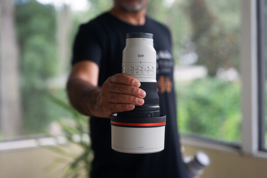 Photographer holding a telephoto lens with white and black barrel