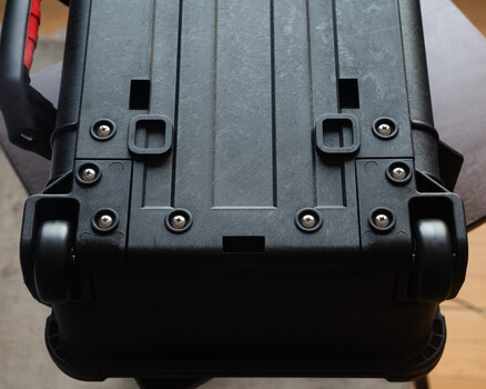 Bottom view of a hard-shell protective case with dual wheels and metal latches