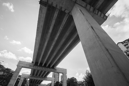 Upward perspective of concrete highway overpass with ribbed underside against cloudy sky