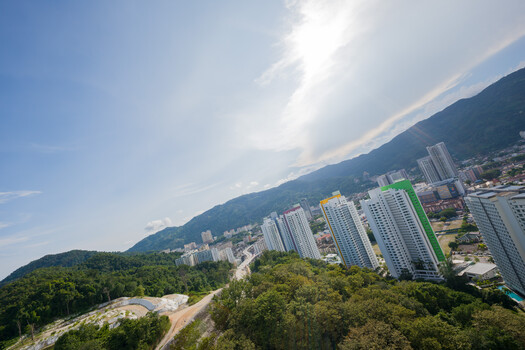 Aerial view of a modern residential development nestled between forested mountains and hillside