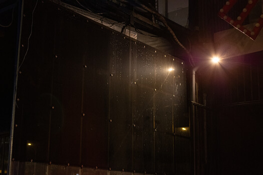 Night scene with overhead power lines and street lights illuminating rain or moisture