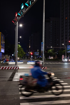 Motorcyclist crossing urban street at night with motion blur
