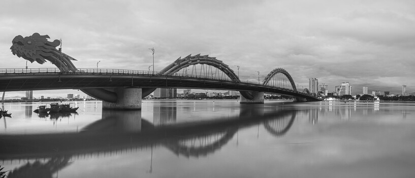 Dragon bridge with serpentine sculptures spanning calm river at dawn