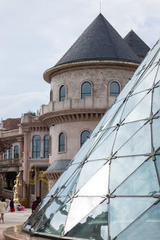 Victorian turret with conical roof beside modern glass and steel architectural structure