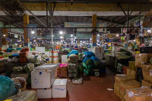 Bustling indoor market warehouse with vendors, merchandise, and crowds under industrial ceiling