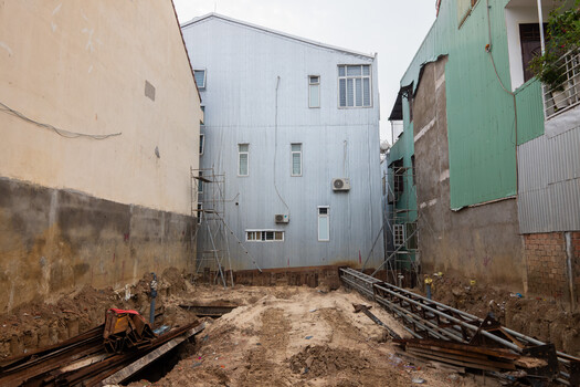 Narrow alleyway between weathered buildings with central white structure